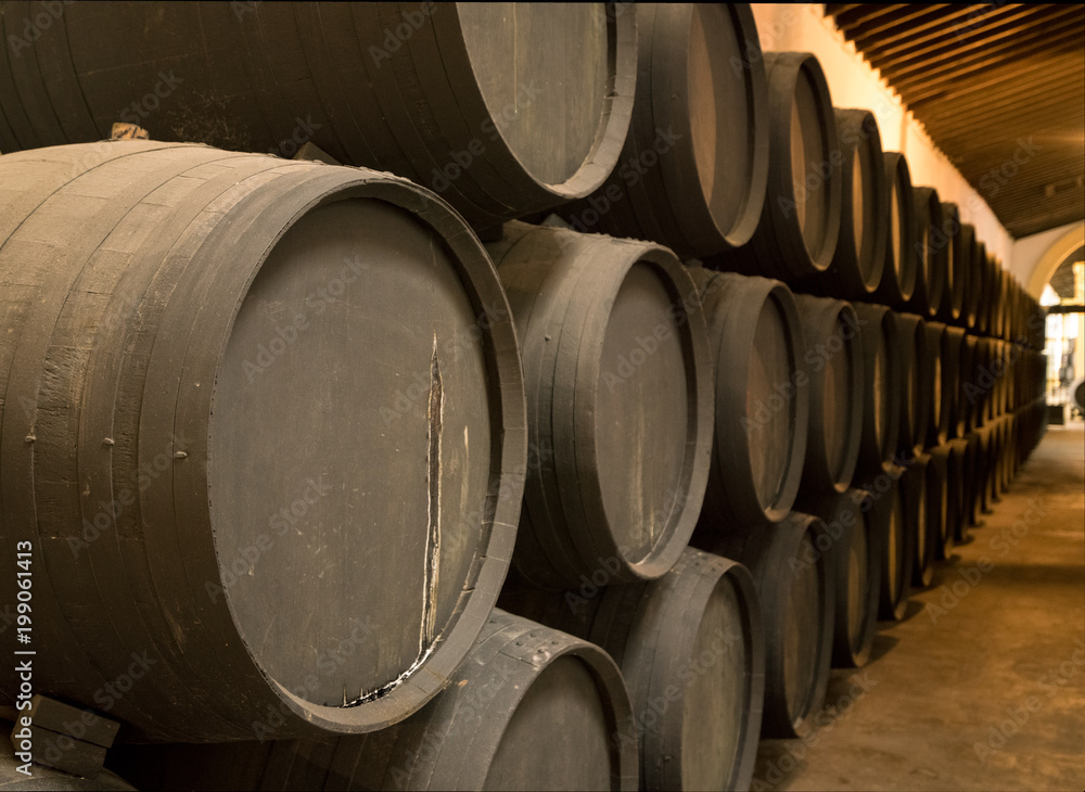 Row of stacked wooden wine barrels for sherry aging Row of stacked wooden wine barrels for sherry aging