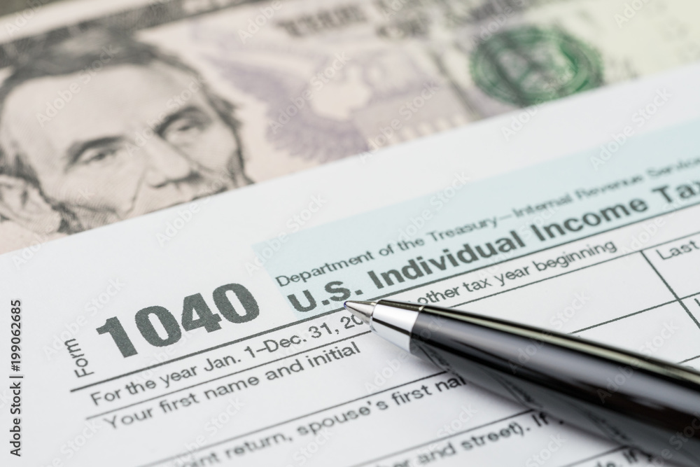 Tax time concept, pen on 1040 US individual income tax filling form with US dollar bill, calculate from yearly revenue to pay the government Tax time concept, pen on 1040 US individual income tax filling form with US dollar bill, calculate from yearly revenue to pay the government