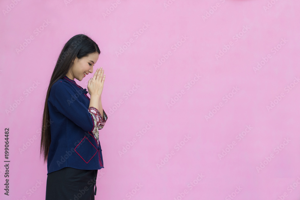 Portrait of asian young girl in traditional thai dress praying isolated on pink background. Wai Sawatdee mean welcome to Thailand. Amazing Travel to Thailand Concept. symbol of Thailand.. Portrait of asian young girl in traditional thai dress praying isolated on pink background. Wai Sawatdee mean welcome to Thailand. Amazing Travel to Thailand Concept. symbol of Thailand..