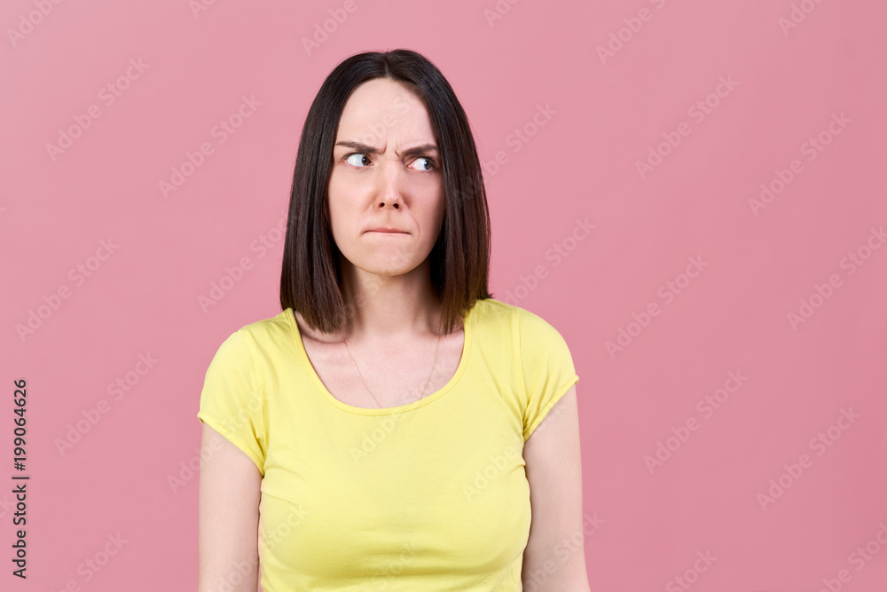 Obraz premium dark-haired girl resentfully inflated her lips and looks irritably to the side, frowning her eyebrows.