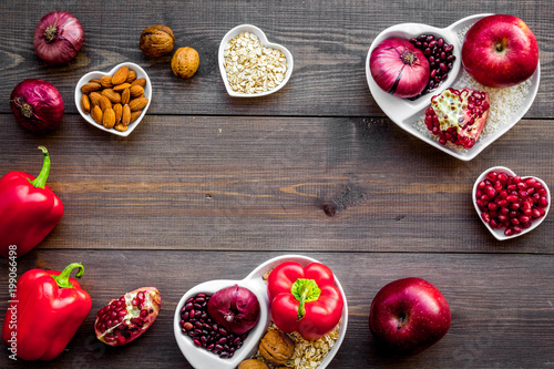 Food which help heart stay healthy. Vegetables  fruits  nuts in heart shaped bowl on dark wooden background top view copy space