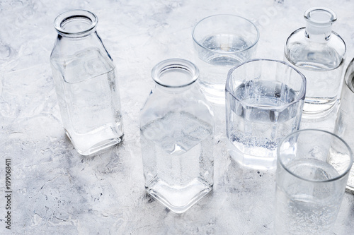 Drinks on the table. Pure water in jar and glasses on grey background
