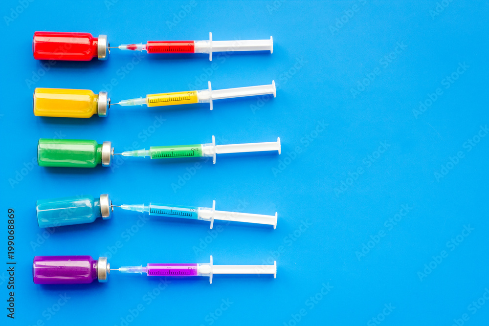 Medical injection. Syringe and bottle with remedy on blue background top view copy space