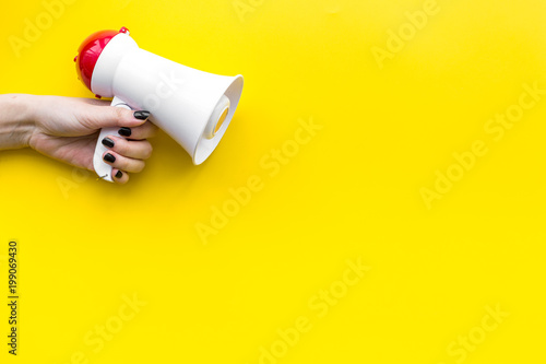 Attract attention concept. Megaphone in hand on yellow background top view copy space