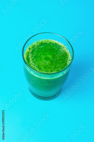 Glass with Green Fresh Raw Smoothie from Leafy Greens Vegetables Fruits Spinach Apples Bananas Kiwi Zucchini on Light Blue Background. Healthy Lifestyle Detox Vitamins Energy Freshness Concept