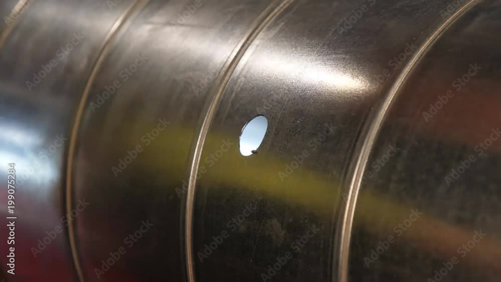 Close up of man's hands holding electrical power cordless drill and cutting hole in galvanized