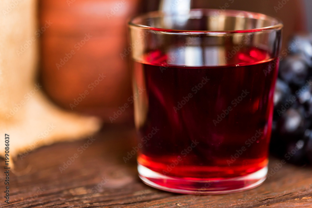 Red grape juice in glass and grapes close Red grape juice in glass and grapes close