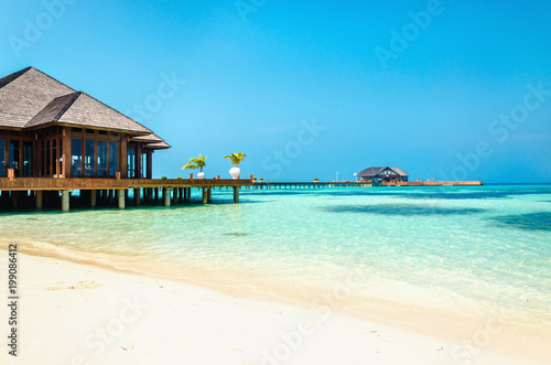 Luxury wooden house on stilts on the background of azure water and beautiful sunny sky
