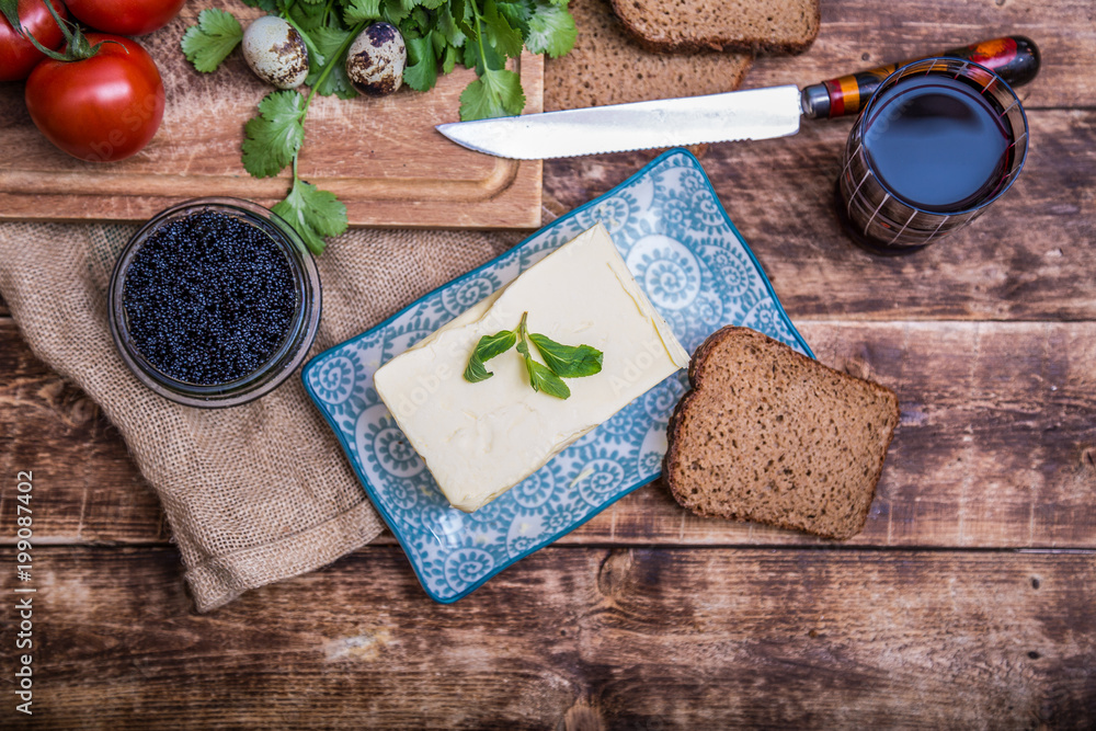 Natural food and ingredients, breakfast with butter, bread and black caviar on wooden background Natural food and ingredients, breakfast with butter, bread and black caviar on wooden background