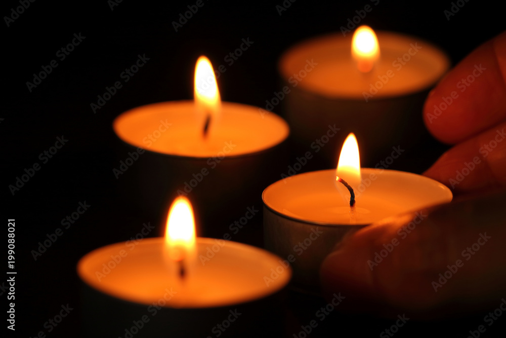 Many candle flames glowing in the dark.