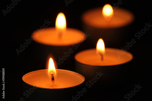 Many candle flames glowing in the dark.