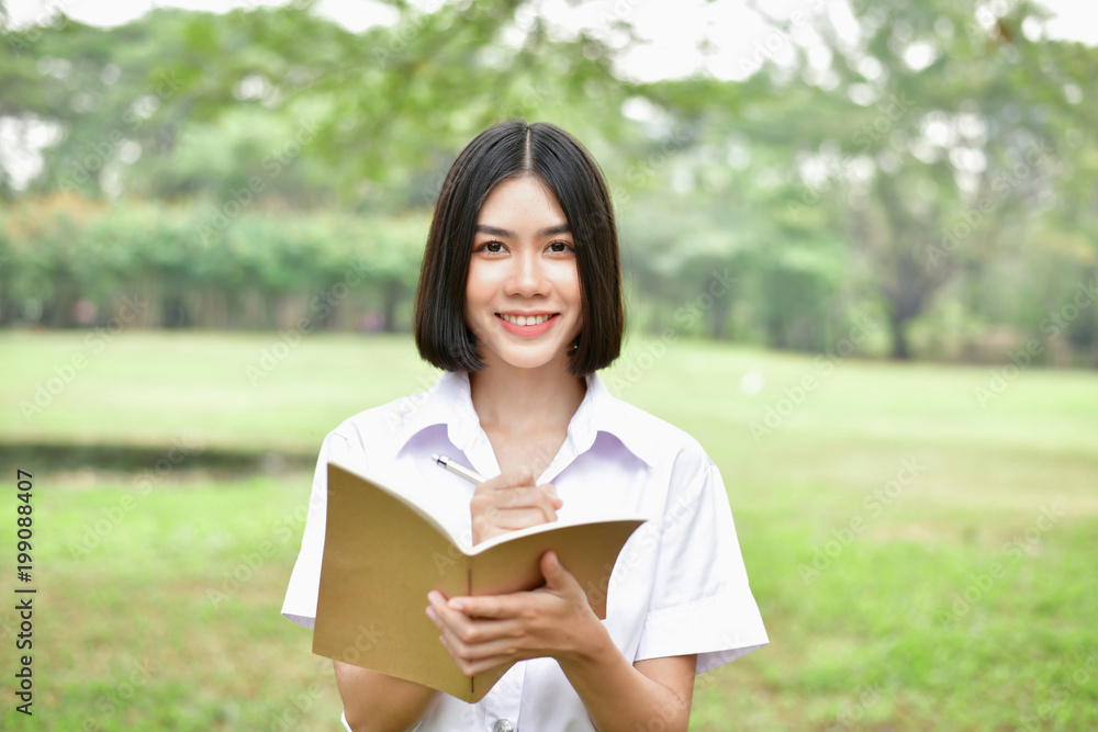 Education Concepts. Beautiful student reading books in the park. Beautiful girl are relaxing in the park. Young student are happy to read. Young student love to study. Education of Asian Women. Education Concepts. Beautiful student reading books in the park. Beautiful girl are relaxing in the park. Young student are happy to read. Young student love to study. Education of Asian Women.