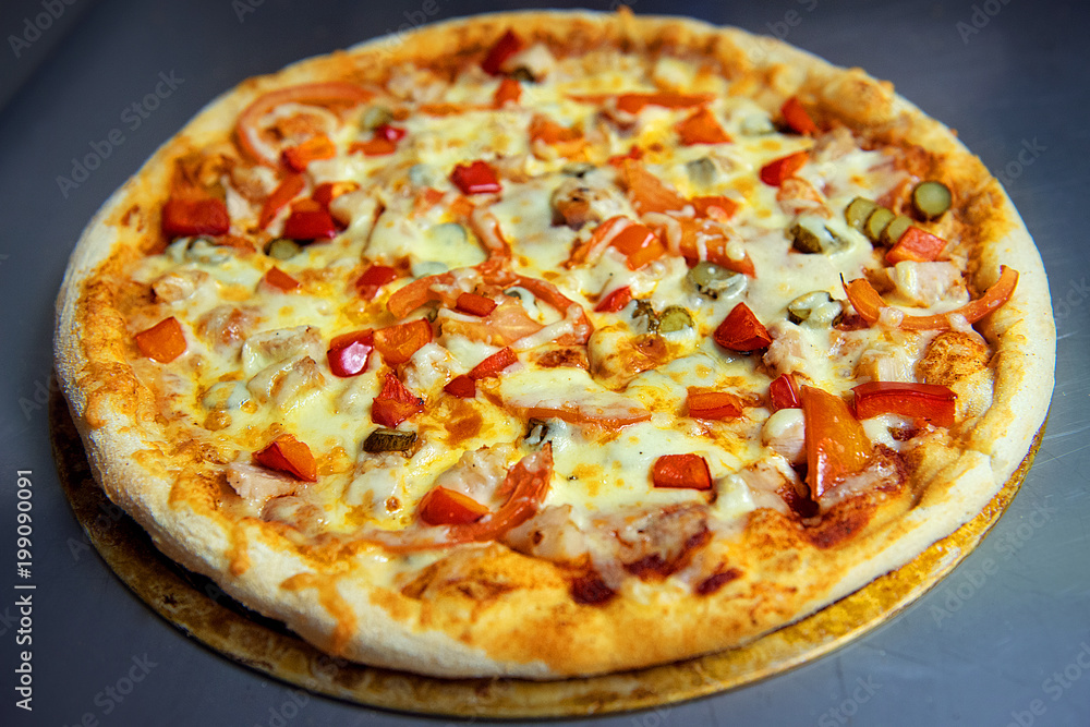 Delicious pizza with vegetables and smoked chicken on the kitchen table.