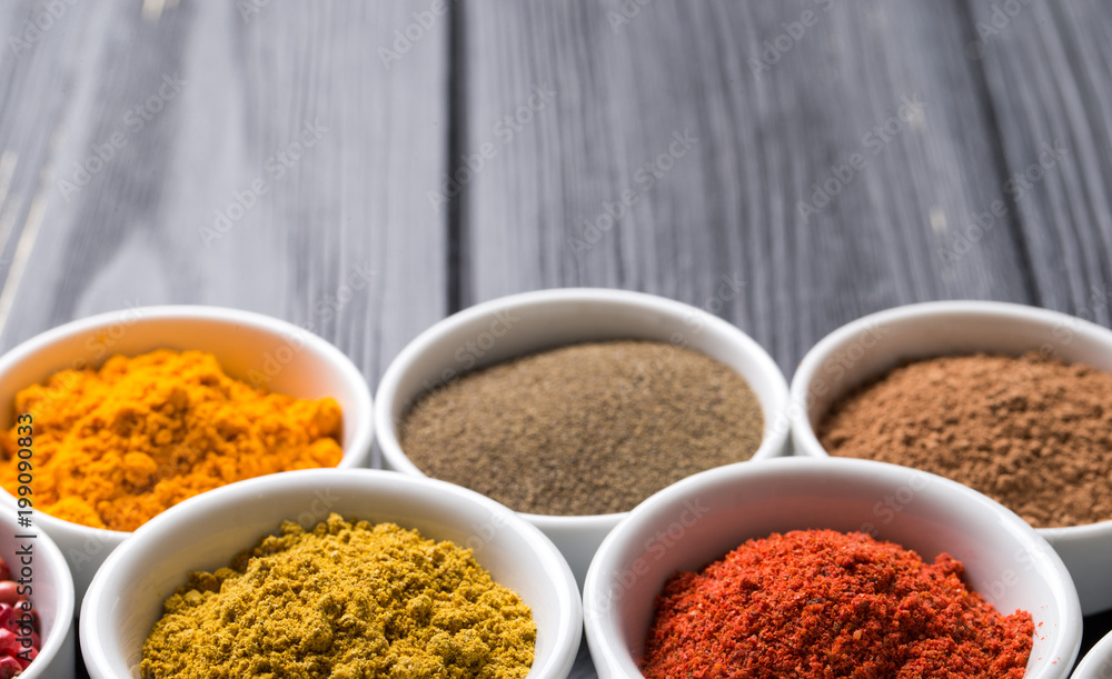 colorful spices in ceramic containers on a dark background colorful spices in ceramic containers on a dark background