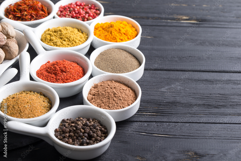 colorful spices in ceramic containers on a dark background