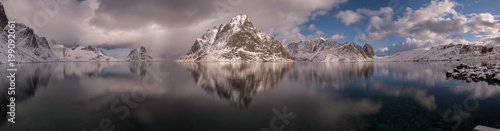 panorama norwegian fjord, reflection in a water, with snow covered mountains