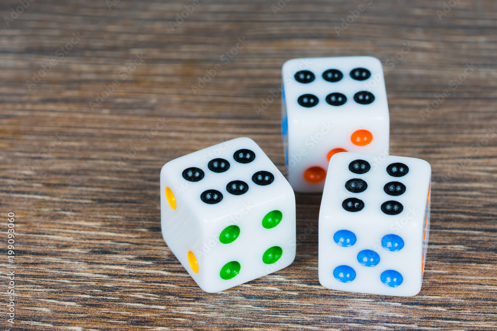 white dices with colorful dots on wooden table