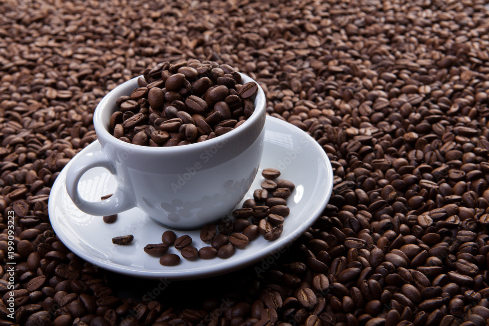 Fototapeta premium white cup of coffee at coffee beans backgrounds