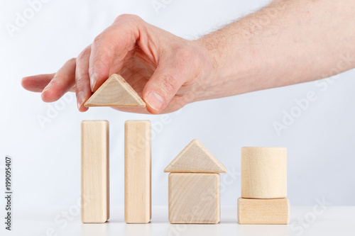 the hand of man builds a house out of children's blocks
