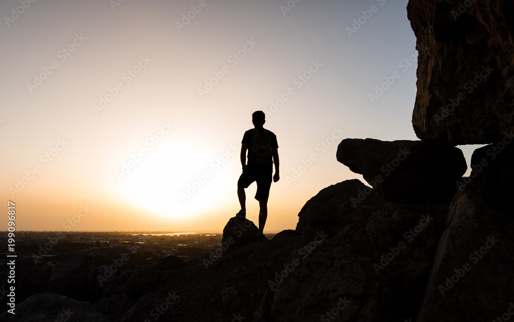 Hiker on the mountain top facing the sunset