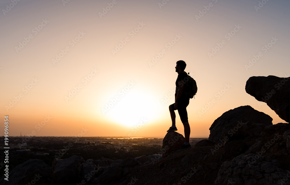 Obraz premium Hiker on the mountain top facing the sunset