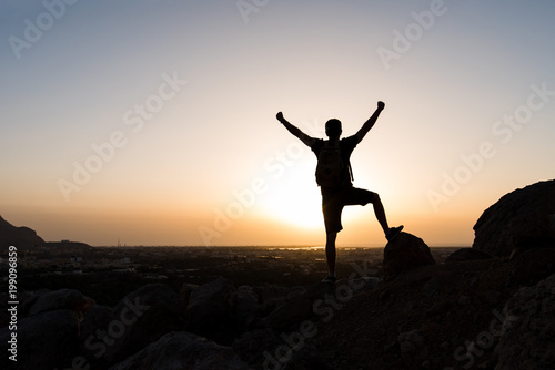 Hiker on the mountain top facing the sunset