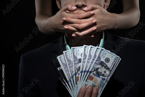 Billede på lærred Woman closes mouth a man in suit holds money