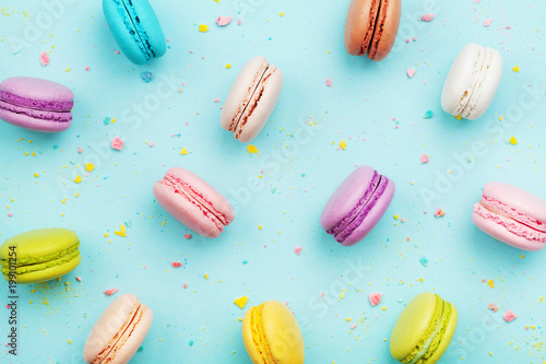 Colorful cake macaron or macaroon on turquoise pastel background from above. French almond cookies on dessert top view. photo