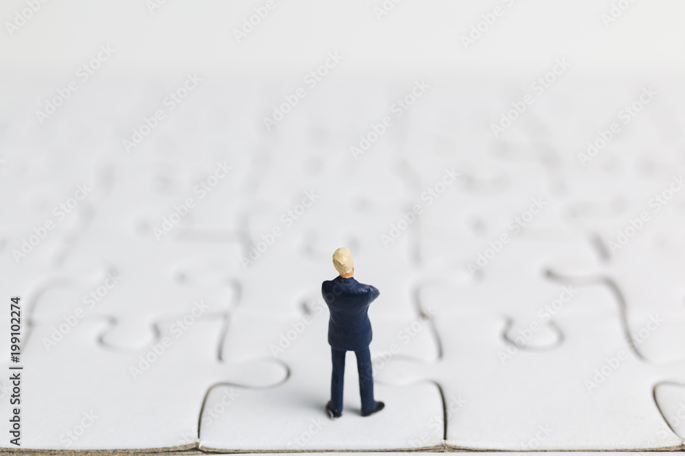 Miniature people: Businessman standing on white jigsaw. Business concept.
Miniature people: Businessman standing on white jigsaw. Business concept.