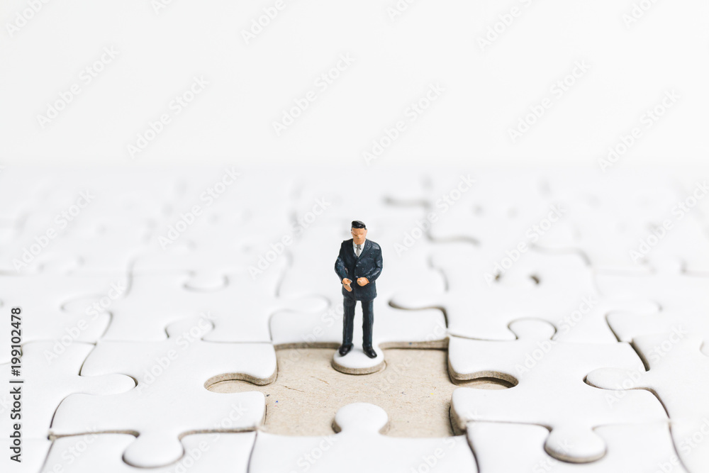 Miniature people: Businessman standing on white jigsaw. Business concept.
Miniature people: Businessman standing on white jigsaw. Business concept.