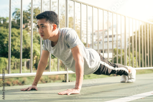 Fitness sport men fashion sportswear doing yoga fitness exercise in street. Fit young asian man doing training workout in morning. Young happy asian man stretching at park after running workout.