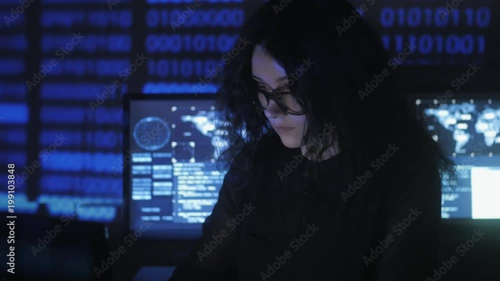 bespectacled Woman Hacker programmer is working on computer in cyber ...