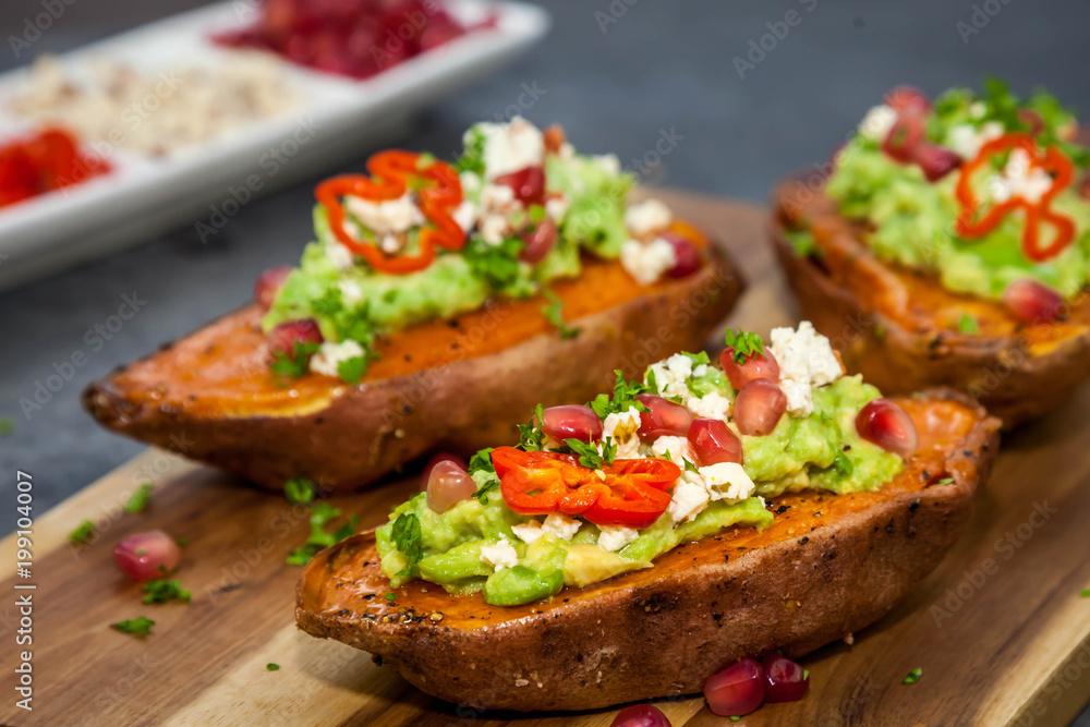 ealthy dinner - Baked sweet potatoes served with guacamole, feta cheese and pomegranate