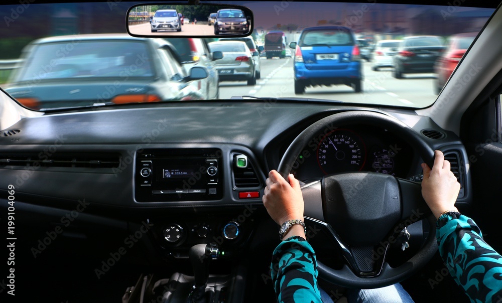 Women driving car with hand on steering wheel looking at the road ahead. Women driving car with hand on steering wheel looking at the road ahead.