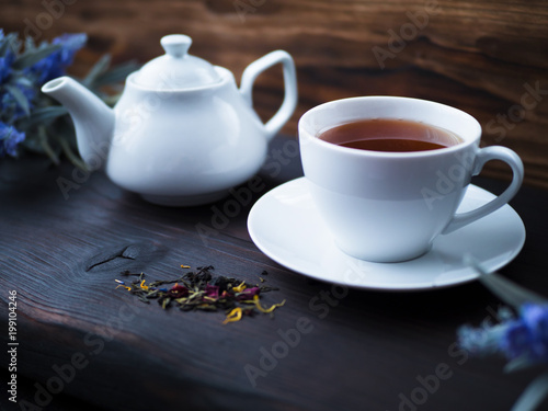 White teapot and Cup of tea on black wooden table and dark still life background