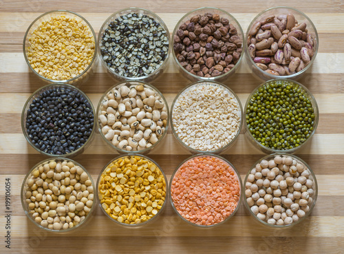 Twelve bowls of lentils and legumes on a chopping board photo