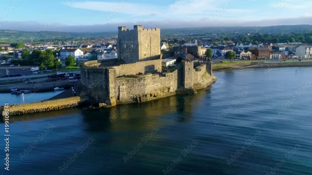 Medieval Norman Castle in Carrickfergus near Belfast in sunrise light. Aerial 4K flyby video with marina, yachts, parking, town and far view of Belfast in the background. Medieval Norman Castle in Carrickfergus near Belfast in sunrise light. Aerial 4K flyby video with marina, yachts, parking, town and far view of Belfast in the background.