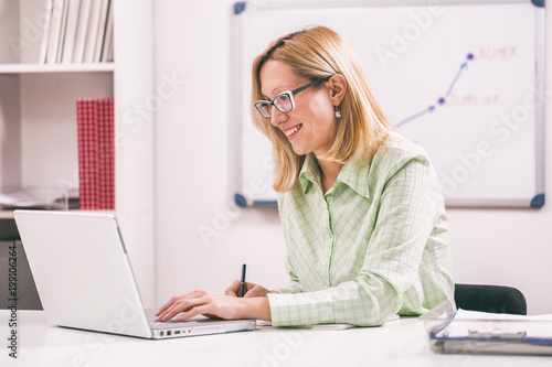 Businesswoman is working on laptop in her office. 