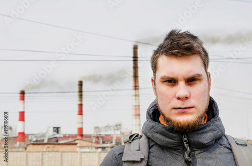 Unhappy young guy on smoking industrial pipes of the Krasnoyarsk. photo