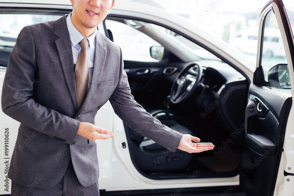 Young chauffeur in business suit welcoming rich and wealthy client on board - rich lifestyle taxi car transportation concept.