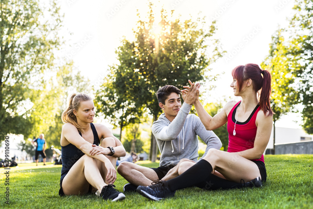 Group of young runners resting in a park. Group of young runners resting in a park.