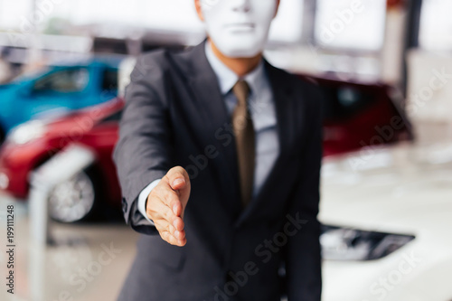 Fotografie Dishonest and evil salesman in business suit in car dealership company handshaking welcome customers to exploit and deceive customers - fraud and bad quality service in business concept