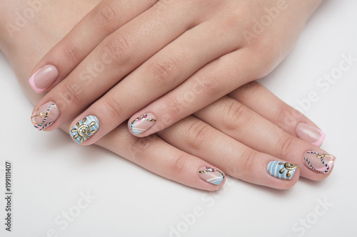 Female hand with turquoise nail design and sea stones. Clean sea water.