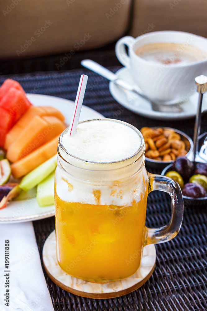 Tropical cocktail, mocktail, juice, refreshing drink from passion fruit in glass jar on table in cafe. Nuts, peanuts, olives, cappuccino coffee and fruits background. Tropical cocktail, mocktail, juice, refreshing drink from passion fruit in glass jar on table in cafe. Nuts, peanuts, olives, cappuccino coffee and fruits background.