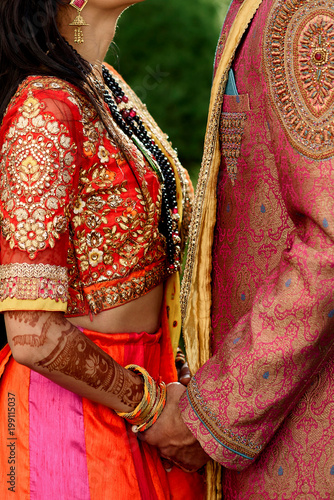 Amazing Indian newlyweds look in each other eyes holding their hands tightly