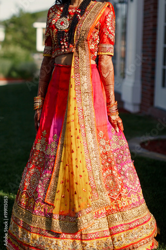Evening sun illuminates rich Indian bride dressed in red saree and lehenga