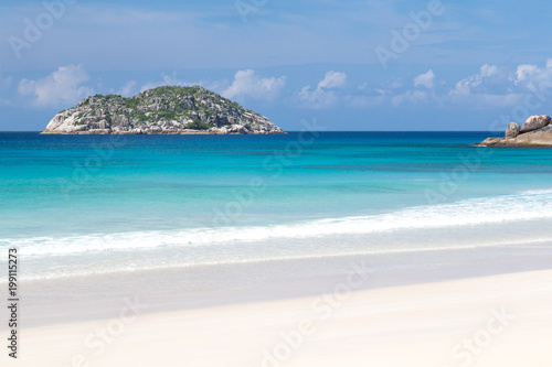 Beach with white sand and blue water with a view to the small island