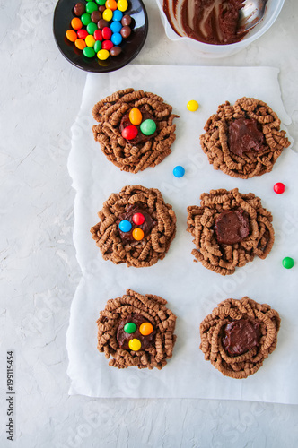 Chocolate bird's nest cookies decorated with colorful candies on a white background.