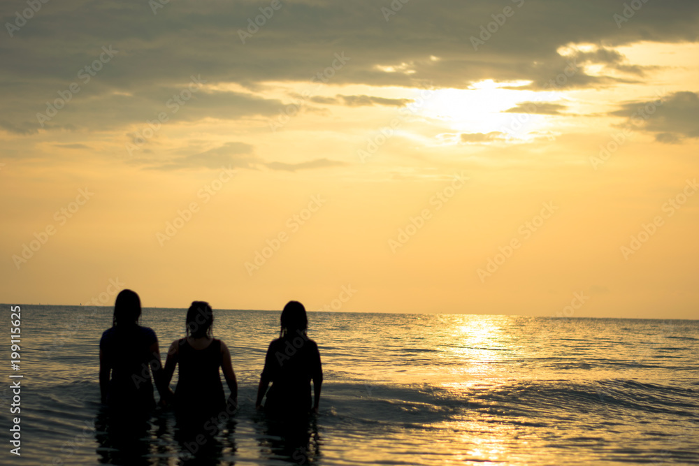 silhouette happy three woman on the sunset beach