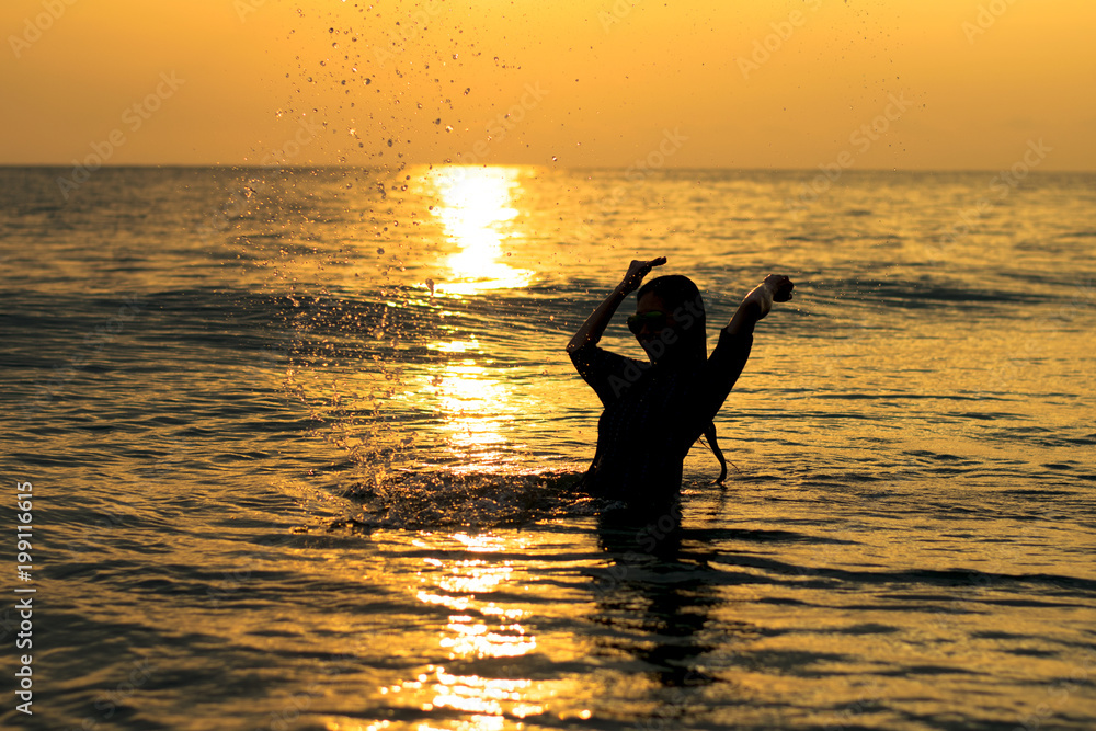 silhouette of a woman playing water sunset on the beach